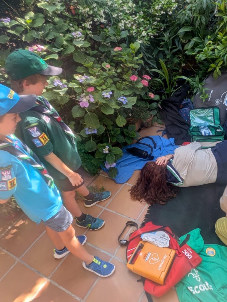 Niños de St. George School aprendiendo a usar un desfibrilador DESA y realizando maniobras de RCP durante el campamento cardioprotegido First Scout.