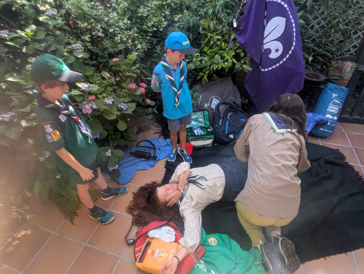 Niños de St. George School aprendiendo a usar un desfibrilador DESA y realizando maniobras de RCP durante el campamento cardioprotegido First Scout.